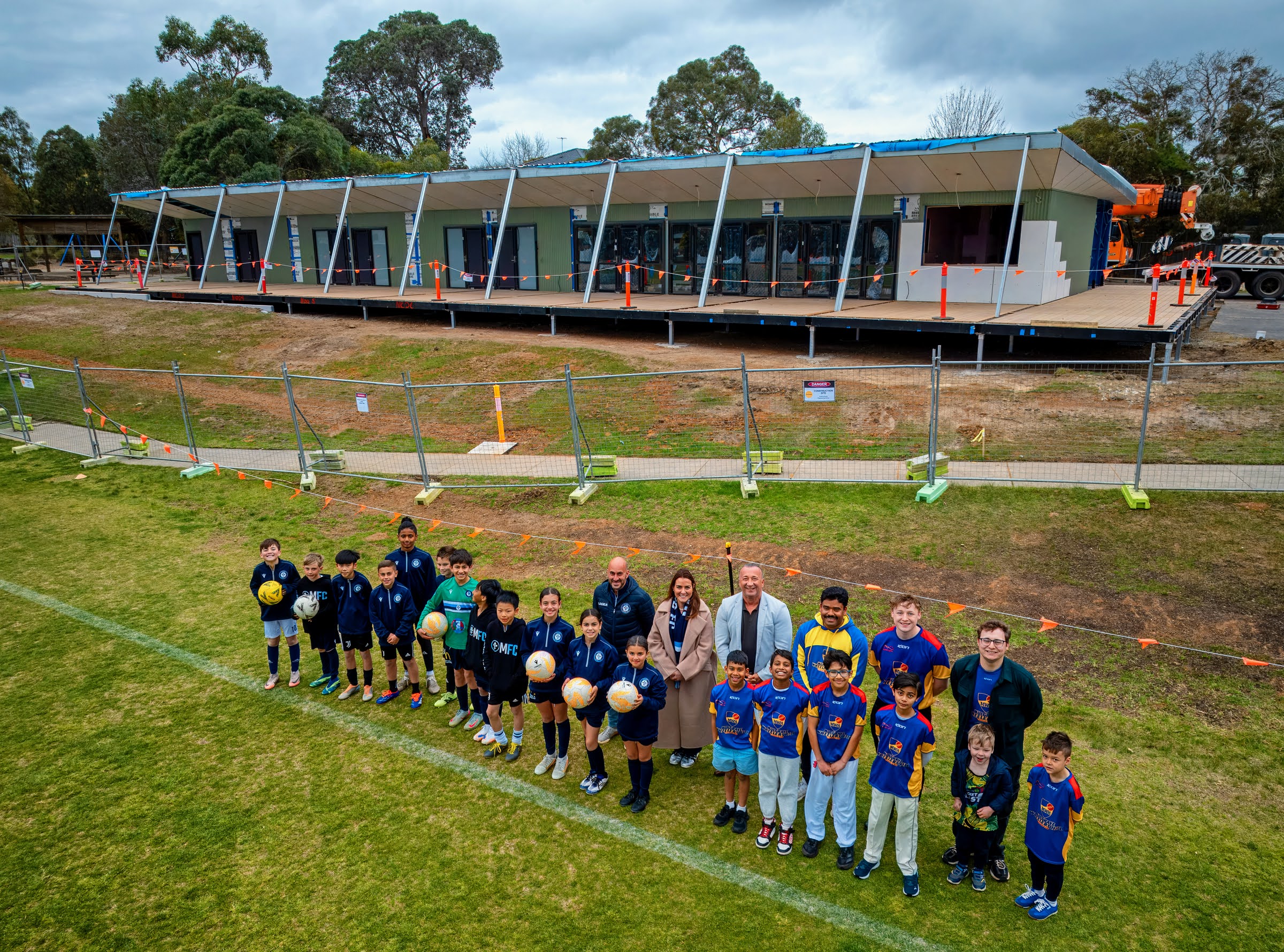 Monash Mayor Paul Klisaris standing with Mazenod Football Club, Mulgrave Wheelers Hill Cricket Club and contractors Shape in front of an in-progress Brandon Park Reserve pavilion 